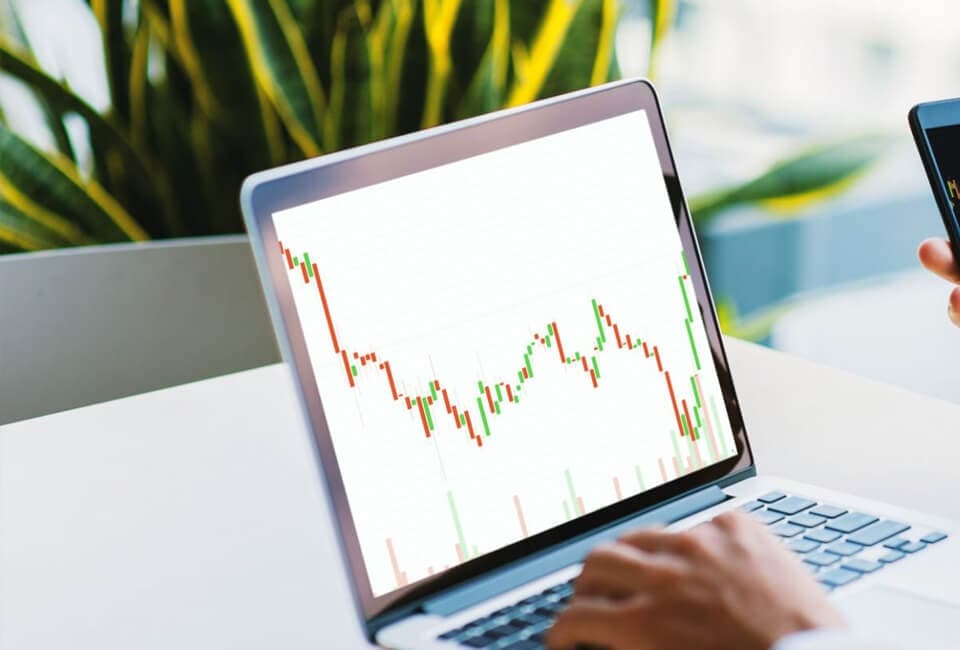 A person analyzing a stock market chart on a laptop.